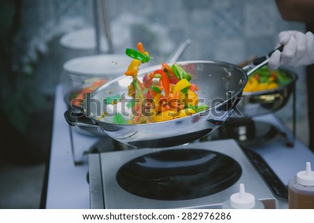 Chef cooking vegetables in wok pan. Shallow dof