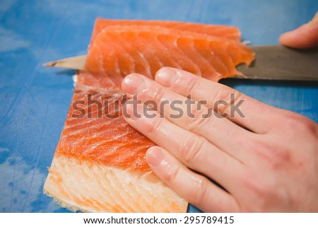 Cutting the salmon with a knife,Japanese chef making sashimi in kitchen,Sushi are made