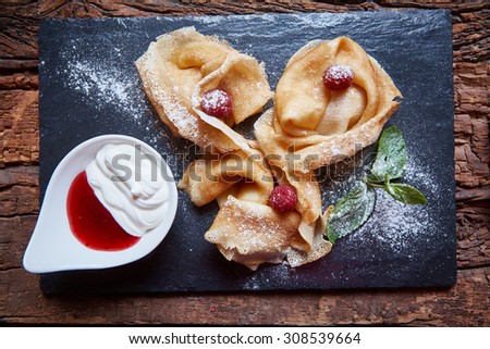 Crepes with raspberries with copy space on black background