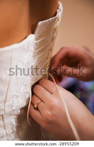 Female hands tightening a corset to the bride. Semi-antique processing