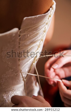 Female hands tightening a corset to the bride. Semi-antique processing