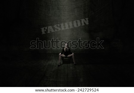 model sitting with open legs in a dark fashionable room