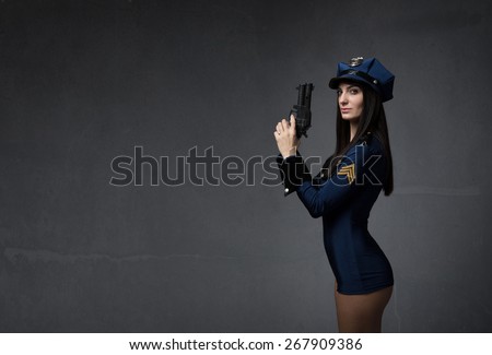 girl in police uniform and gun on hand, dark background
