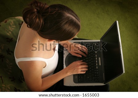 Young woman in leisure clothing using a laptop.  From directly above.