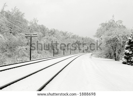 Winter scene with train tracks and snow-covered trees.