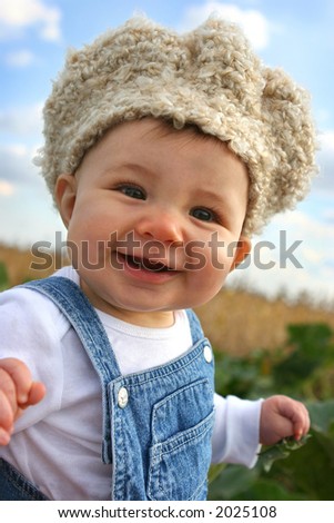 baby in overalls and crocheted hat