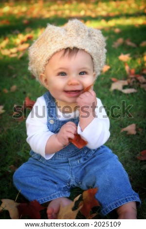 baby in overalls and crocheted hat with leaves