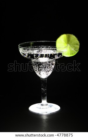 lime and carbonated beverage in margarita glass lit from beneath.