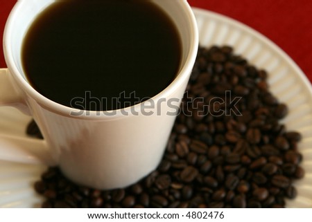cup of coffee with plate of beans and red cloth, shallow depth of field