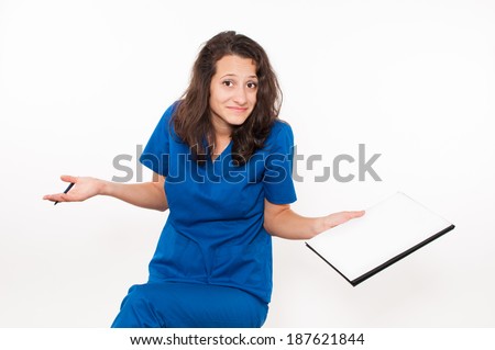 Confused young female doctor in blue coat holding clipboard
