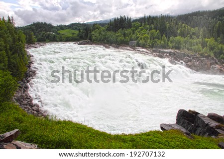 Waterfall and river in green forest in northern Norway at summer
