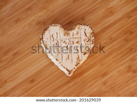 Neufchatel cheese shaped like heart on wooden cutting board
