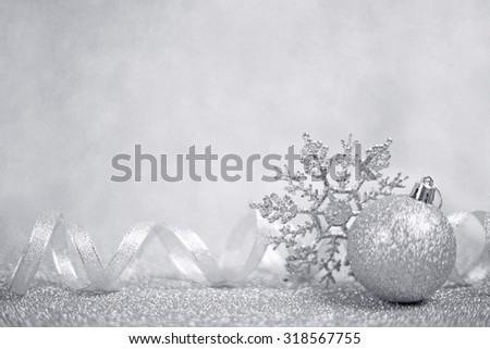 Silver christmas balls and snowflakes on shining glitter background with copy space