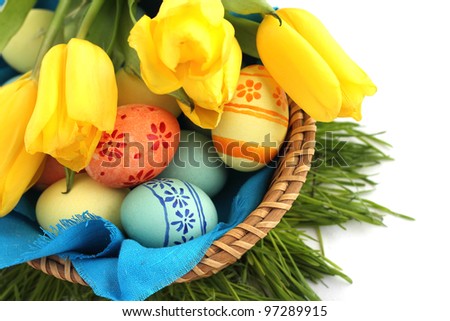 Basket of colored easter eggs and tulips on white background