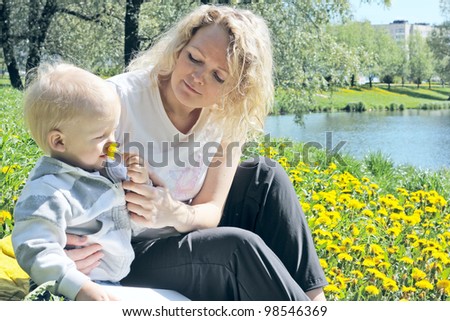 mother and child smelling a flower on spring field