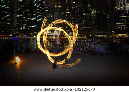 SINGAPORE - MARCH 15, 2014: Fire Dancer street performance using fire poi, at Marina Bay.