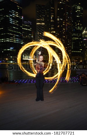 SINGAPORE - MARCH 15, 2014: Fire Dancer street performance using fire poi, at Marina Bay.