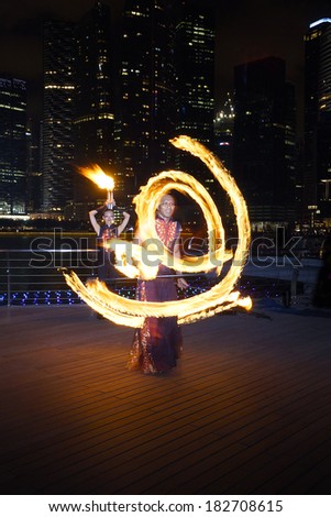 SINGAPORE - MARCH 15, 2014: Fire Dancer street performance using fire staff, at Marina Bay.