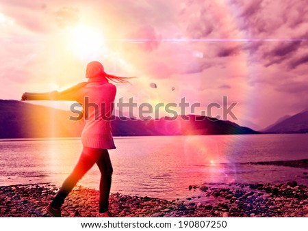 girl throwing stones into a lake in sunset