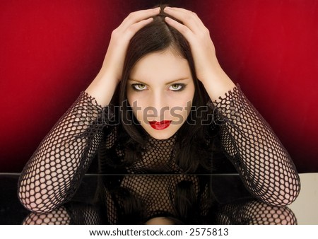 woman with dark hair and red lips wearing a black net-shirt