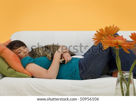 young woman sleeping on a sofa with a little cat