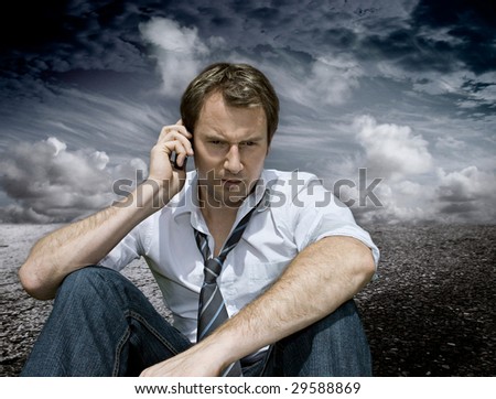 businessman with handy on a road with dark clouds behind