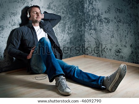 smart man leaning against a wall, listening to relaxing music