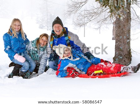 young funny family with sledge under a tree in winter-landscape