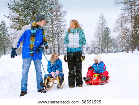 young funny family is sledging in winter-landscape