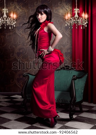 beautiful woman in evening dress standing in front of an victorian chair