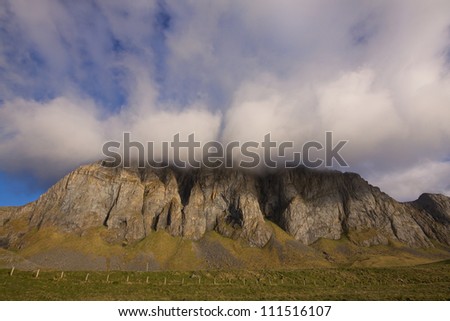 Dramatic view of cloudy cliffs on remote island of Vaeroy in north Atlantic, Lofoten islands, Norway