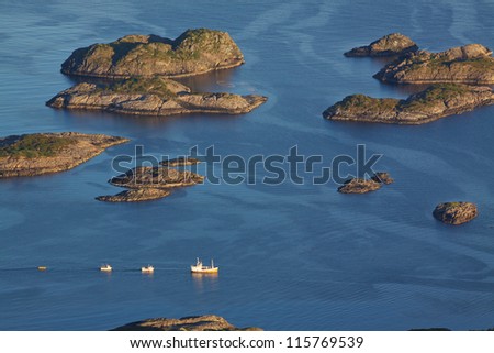 Bird eye view of fishing boats sailing between by rocky islets near Henningsvaer on Lofoten islands in Norway