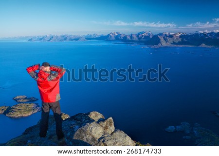 Active man standing on the top of mountain Festvagtinden viewing picturesque scenery of Lofoten islands, Norway