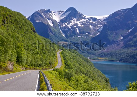 Coastal road in Norway leading to Bodo with snowy mountains of Saltfjellet-Svartisen National Park in the background