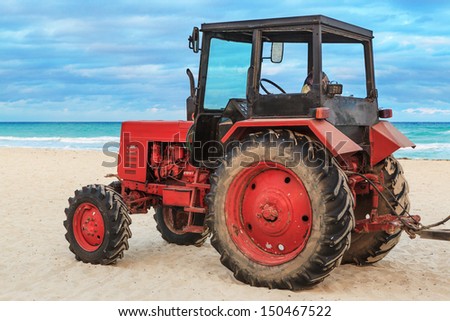 old red tractor on the sandy beach