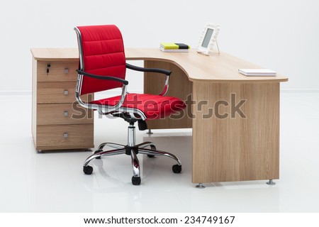 wood desk and red armchair on a white wall