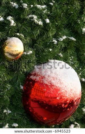 Yellow and red sphere under a snow on a christmas tree