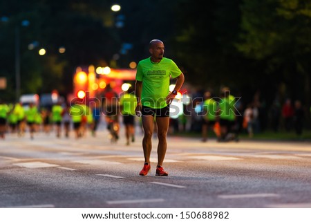 STOCKHOLM - AUG, 17: Just before the start of the Midnight Run (Midnattsloppet) event, a man warming up, the start in visible in blurred background. Aug 17, 2013 in Stockholm, Sweden