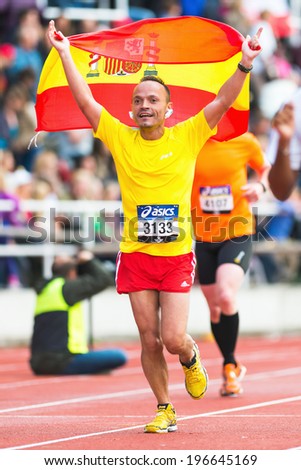 STOCKHOLM - MAY 31: Happy spanish man running and waving the spanish flag in the final stretch at Stockholm Stadion in ASICS Stockholm Marathon 2014. May 31, 2014 in Stockholm, Sweden.