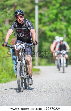 TULLINGE, STOCKHOLM - JUNE 8: Happy mountain bike cyclist on a gravel road at Lida loop race 2014 during a sunny day in the Swedish nature. June 8, 2014 in Stockholm, Sweden.