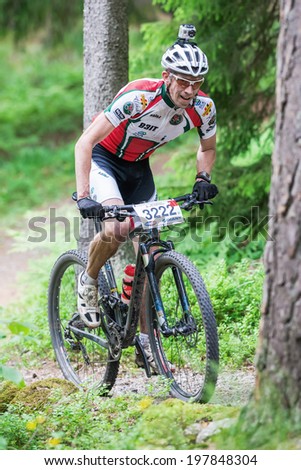 TULLINGE, STOCKHOLM - JUNE 8: Mountain bike cyclist in forest trail with camera on helmet at Lida loop race 2014 during a sunny day in the Swedish nature. June 8, 2014 in Stockholm, Sweden.
