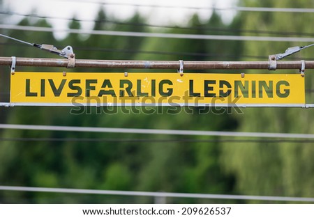 Metal high voltage danger sign and railway electric overhead contact wire all over. In swedish