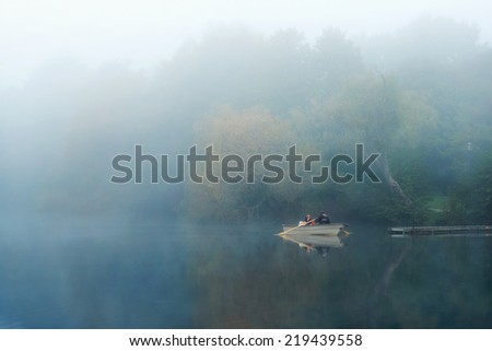 Stockholm, Sweden - Sep 19, 2014: Two men inspecting lake Trekanten with a rowing boat during a early misty morning in Stockholm, Sweden