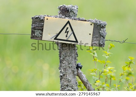 Electrical fence in old style with sign with the electric symbol