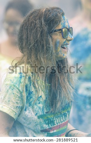 STOCKHOLM, SWEDEN - MAY 23: Happy girl in sideview covered in paint at Stockholm Color Run on May 23, 2015. People from all walks of life participated in the run.