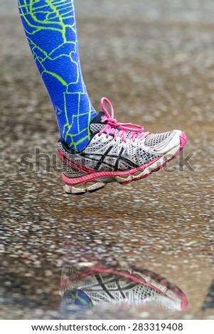 STOCKHOLM - MAY 30: Colored running shoe with blue socks reflecting in puddle at the wet streets of Stockholm in ASICS Stockholm Marathon 2015.