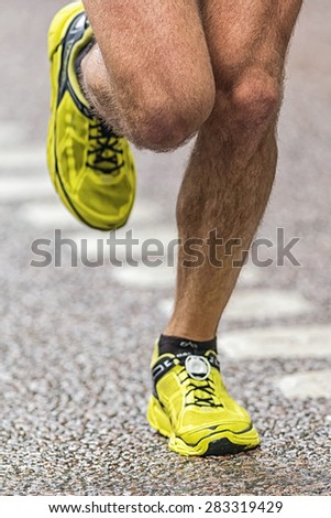 STOCKHOLM - MAY 30: Closeup of a runners legs with colorful yellow shoes at the wet streets of Stockholm in ASICS Stockholm Marathon 2015.