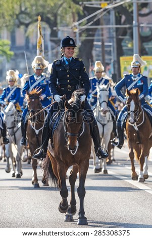 STOCKHOLM - JUN 06, 2015: Happy Police woman on her horse infront of the Swedish Royal Guards in blue uniforms at the swedish national day.