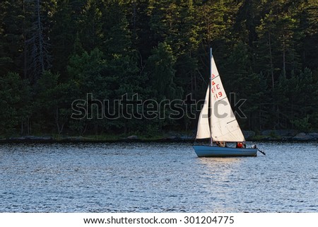 GRISSLEHAMN, SWEDEN - JULY 24, 2015: Small sailboat against a dark green background suring afternoon.