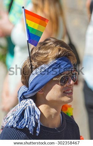 STOCKHOLM, SWEDEN - AUGUST 1, 2015: Close up of a man with the rainbow flag stuck in a head scarf at the Pride parade in Stockholm. Approx 400.000 gathered at the streets.